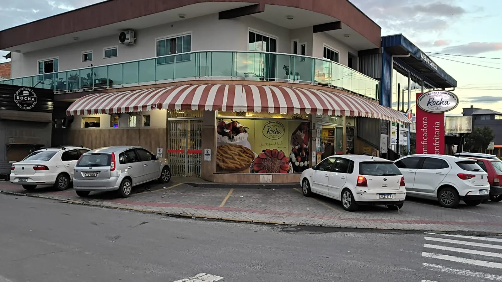 Toldo listrado com bambinela em prédio comercial de esquina, feito pela Tecno Toldos e Lonas